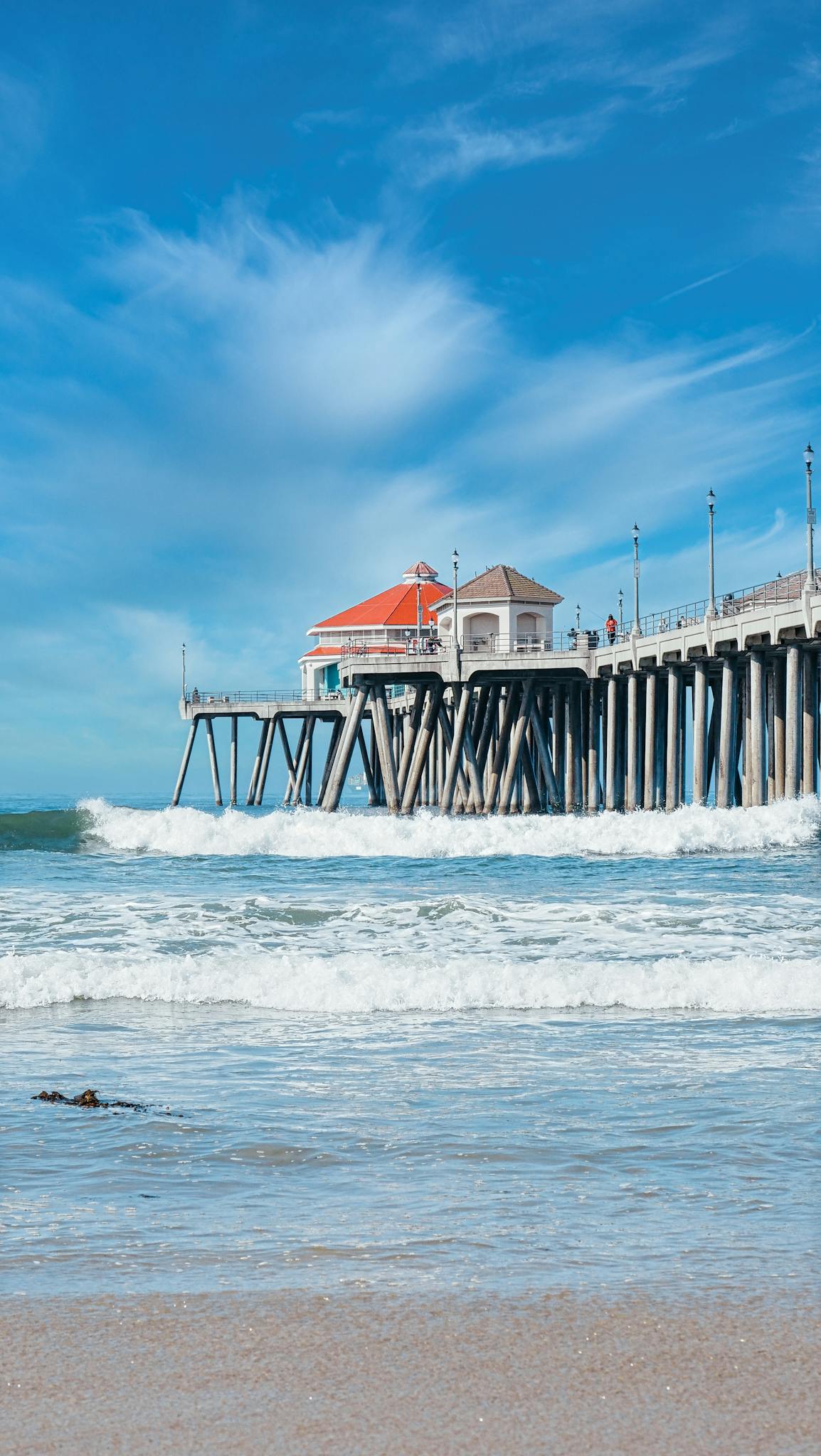 Beautiful view of a pier extending over ocean waves under a blue sky.