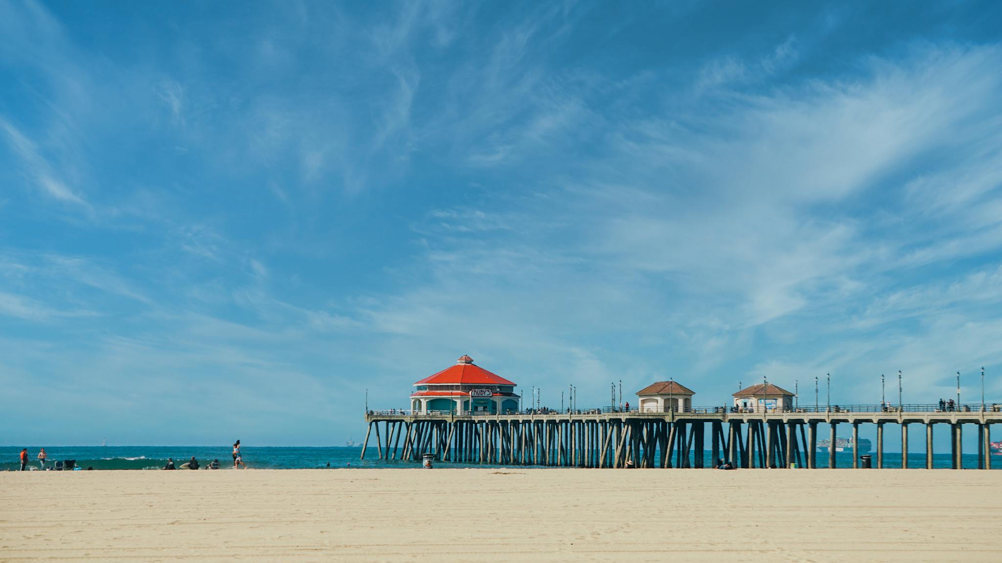 Huntington Beach Pier under a vibrant blue sky with sandy shore, capturing a picturesque coastal scene.