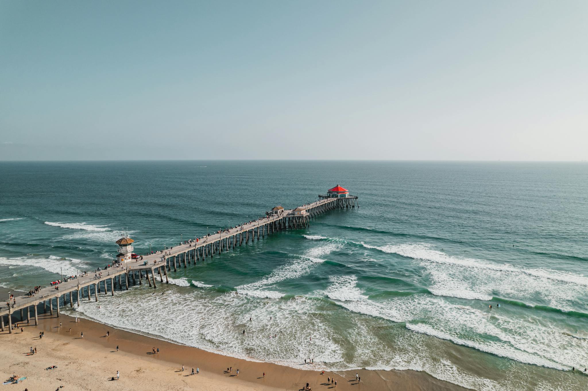 Stunning aerial view of Huntington Beach Pier stretching into the Pacific Ocean under clear skies.